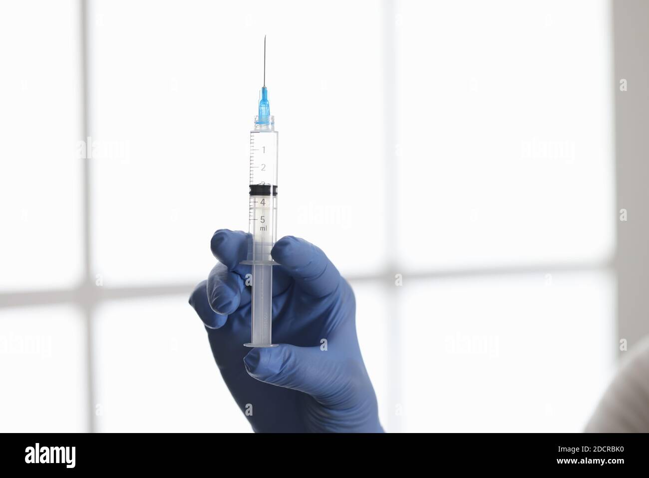 I medici mano nel guanto di gomma che tiene la siringa con il medicinale dentro primo piano della clinica Foto Stock