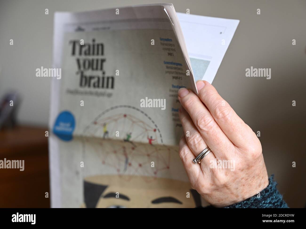 Primo piano di una donna anziana che legge un supplemento di giornale. Foto Stock