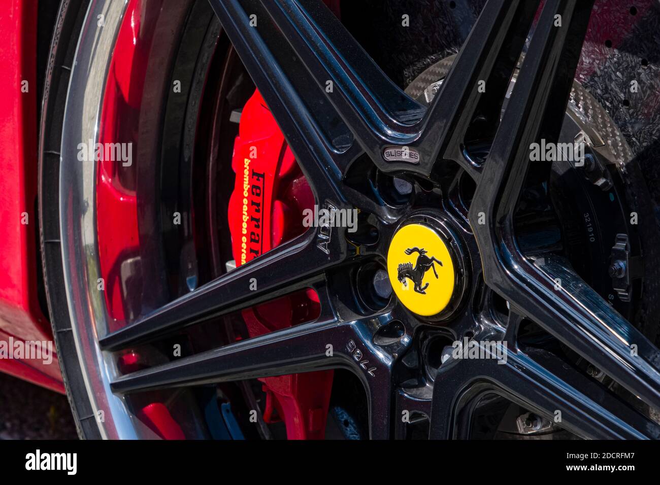 Particolare di una Ferrari rossa con la pinza del freno rossa, parte del cerchio compreso il Cavallino Rampante, uno stallone nero a balza sullo scudo giallo. Foto Stock