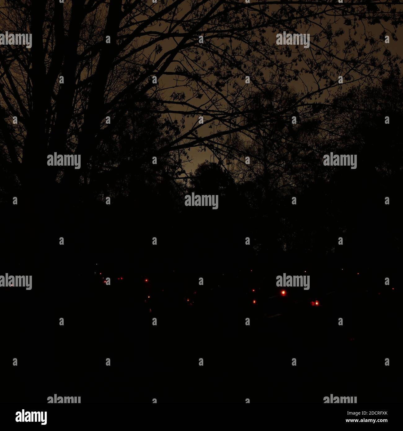 Cimitero con candele rosse sulle tombe di notte con un cielo inquietante sullo sfondo Foto Stock