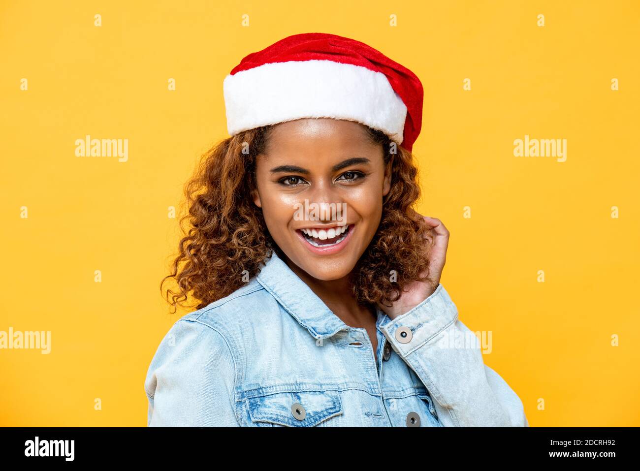 Felice ritratto di sorridente sorpresa afroamericana donna che indossa Natale cappello su sfondo isolato giallo Foto Stock