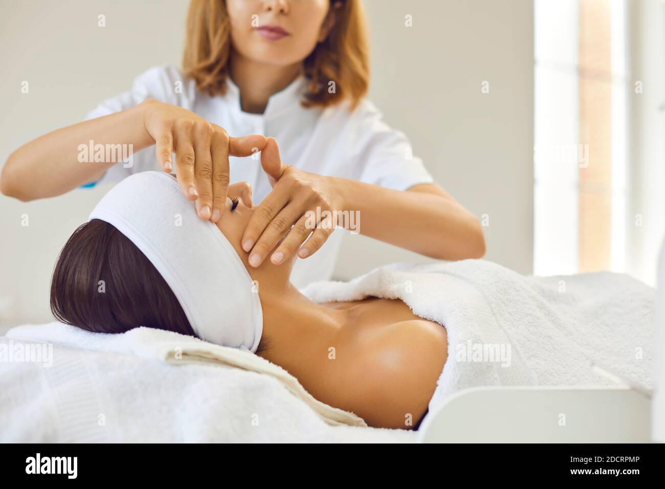 Dermatologo che fa la procedura di massaggio manuale rilassante del viso per la donna nel salone di bellezza Foto Stock