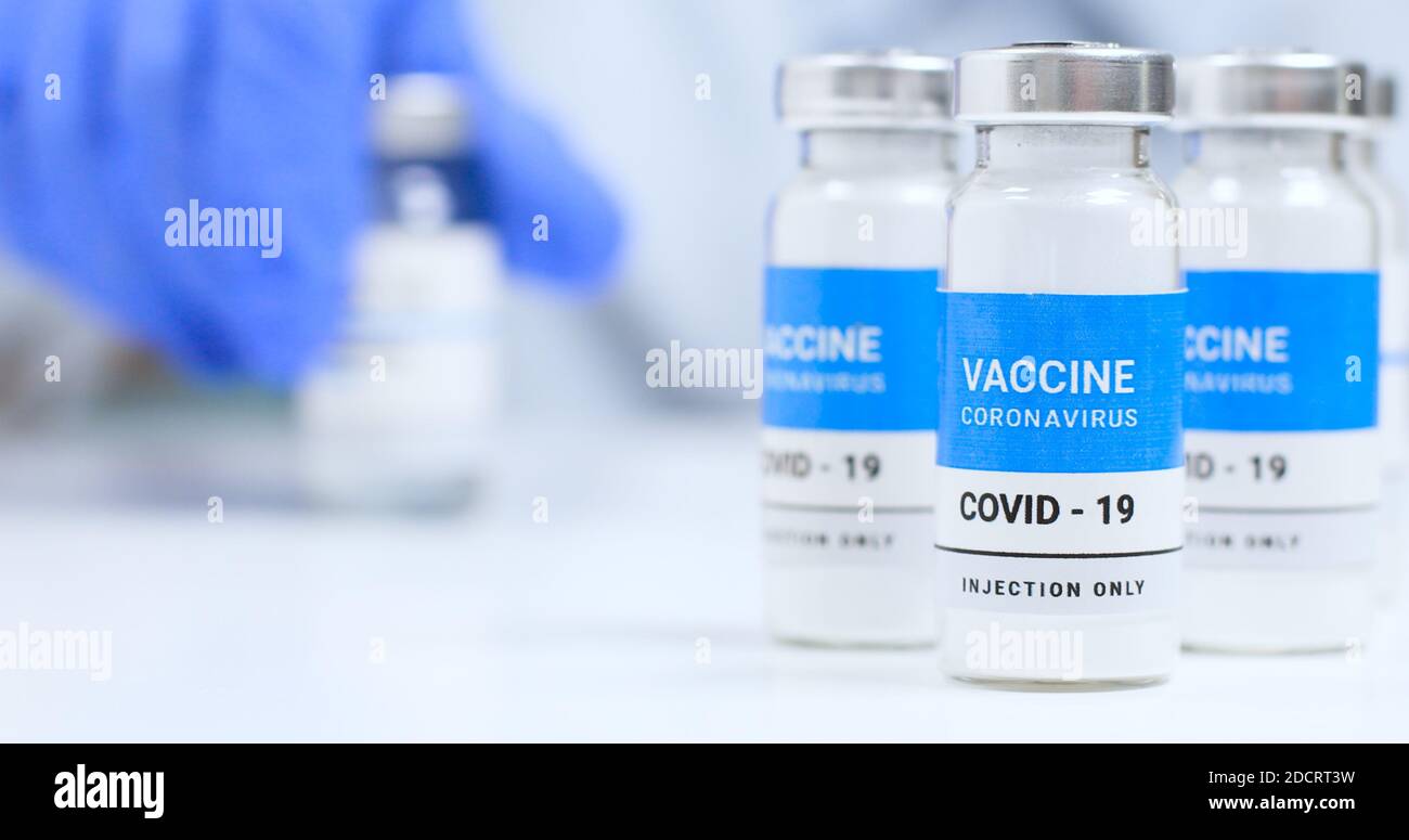 Donna medico mani in guanti medici blu con liquido trasparente flacone vaccino coronavirus e siringa per iniezione in laboratorio. Ricerca e sviluppo di nuove cure per le malattie Foto Stock