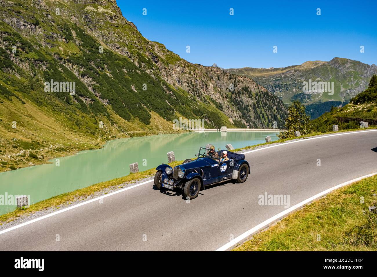 Un'auto d'epoca Invicta Tourer S-Type che oltrepassa un lago sulla Silvretta Hochalpenstrasse durante il raduno di auto d'epoca Arlberg. Foto Stock