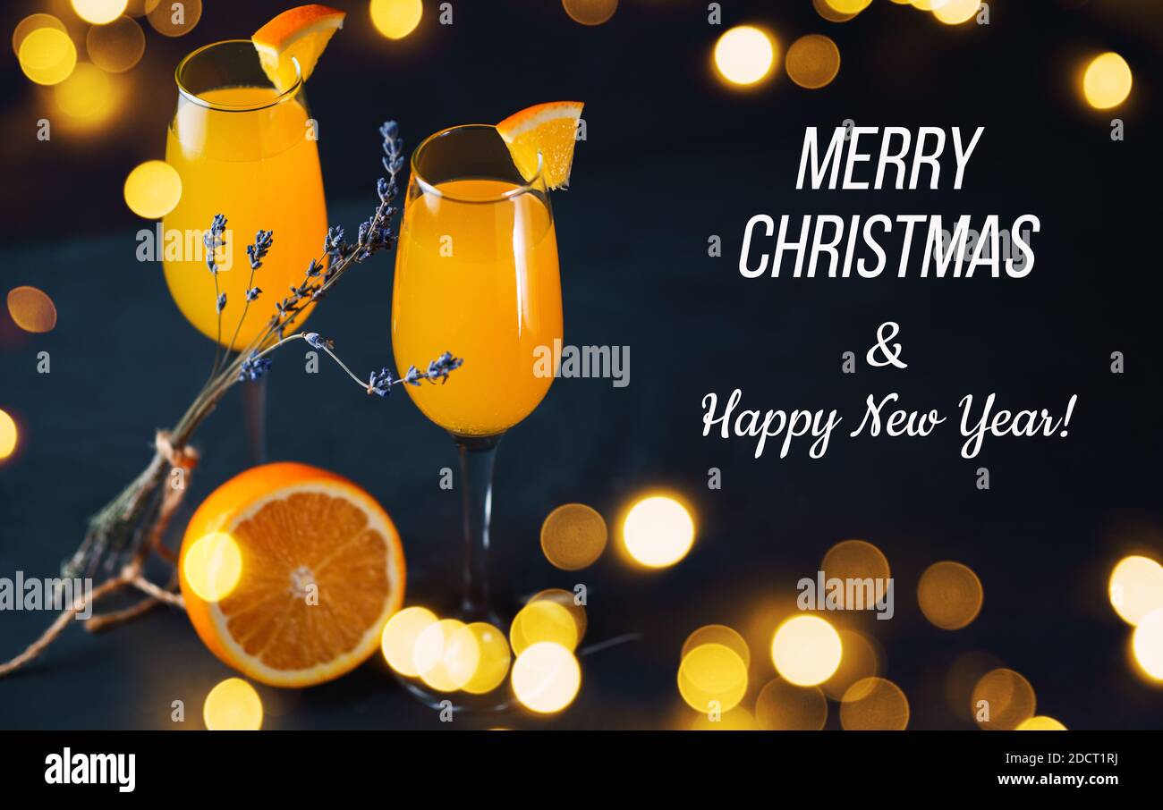 Cocktail Mimosa su sfondo scuro con ghirlande baque, auguri di buon Natale e felice testo del nuovo anno Foto Stock