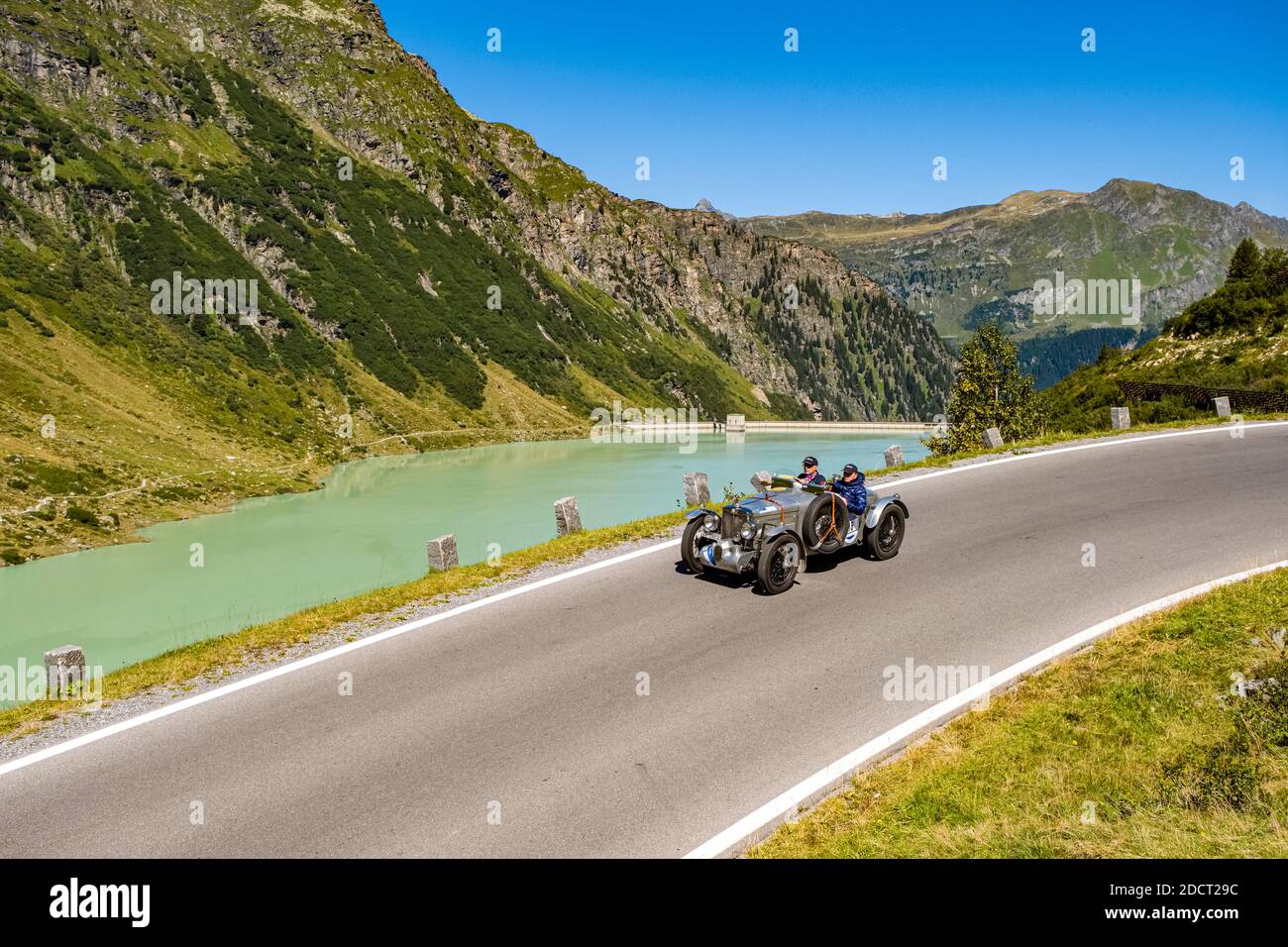 Un'auto d'epoca MG TA Midget Special K 3 che passa accanto a un lago sulla Silvretta Hochalpenstrasse durante il Rally di Arlberg Classic Car. Foto Stock