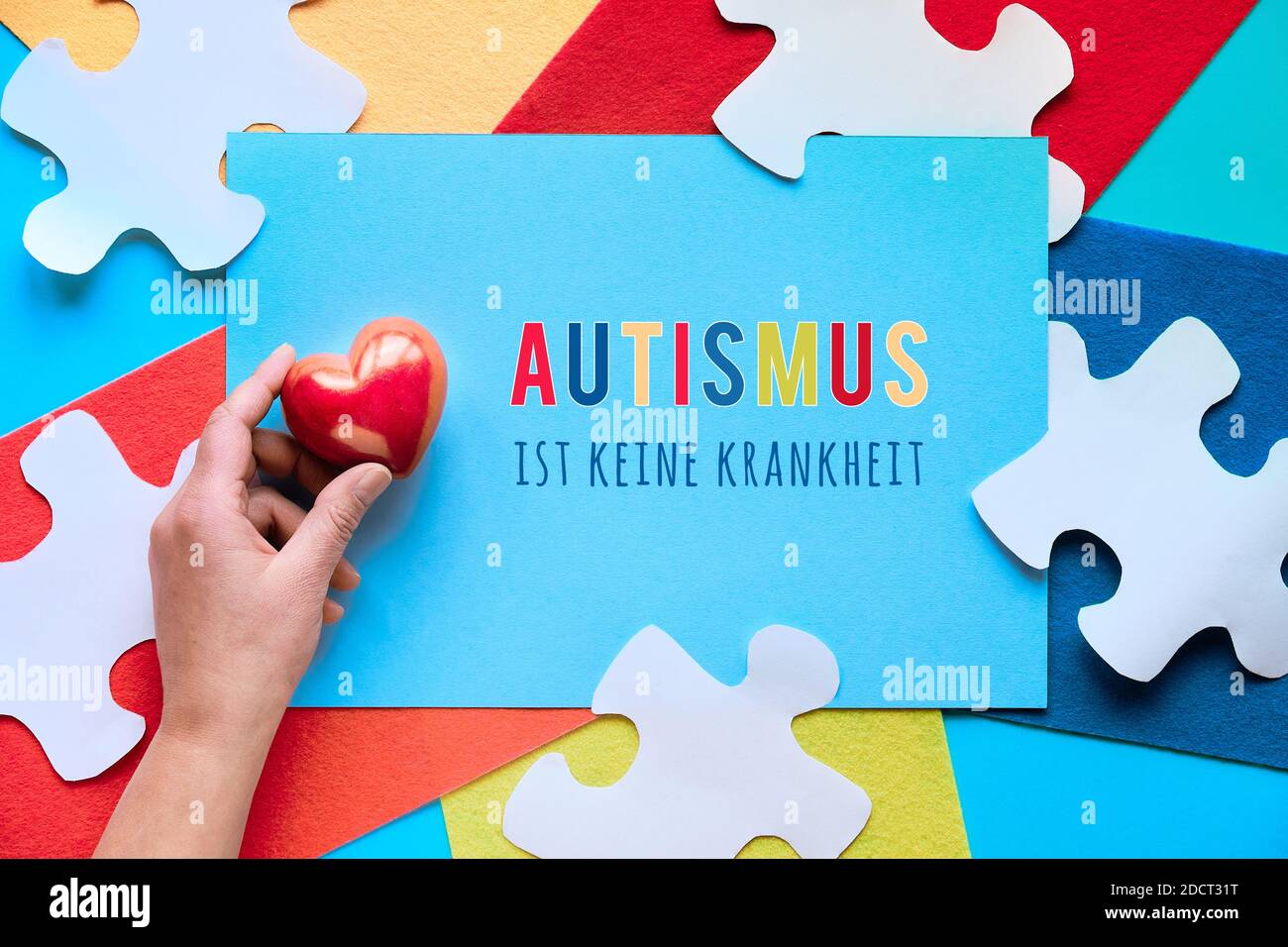 Il testo tedesco significa che l'autismo non è una malattia. Elemento puzzle su elementi in feltro stratificati, vista dall'alto. Foto Stock
