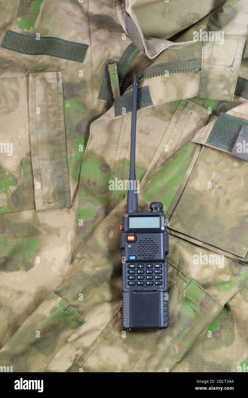 una radio portatile nera giace su una giacca camouflage militare Foto Stock
