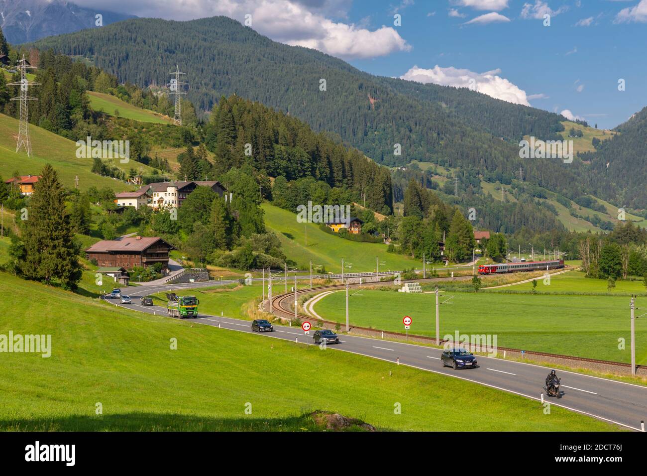 Vista del treno, delle montagne e della strada principale nei pressi di Schladming, Schladming, Stiria, Tirolo austriaco, Austria, Europa Foto Stock