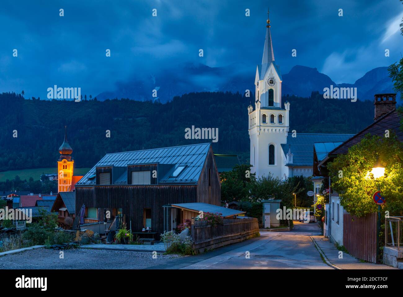 Vista della torre dell'orologio della chiesa con sfondo montuoso al tramonto, Schladming, Stiria, Tirolo austriaco, Austria, Europa Foto Stock