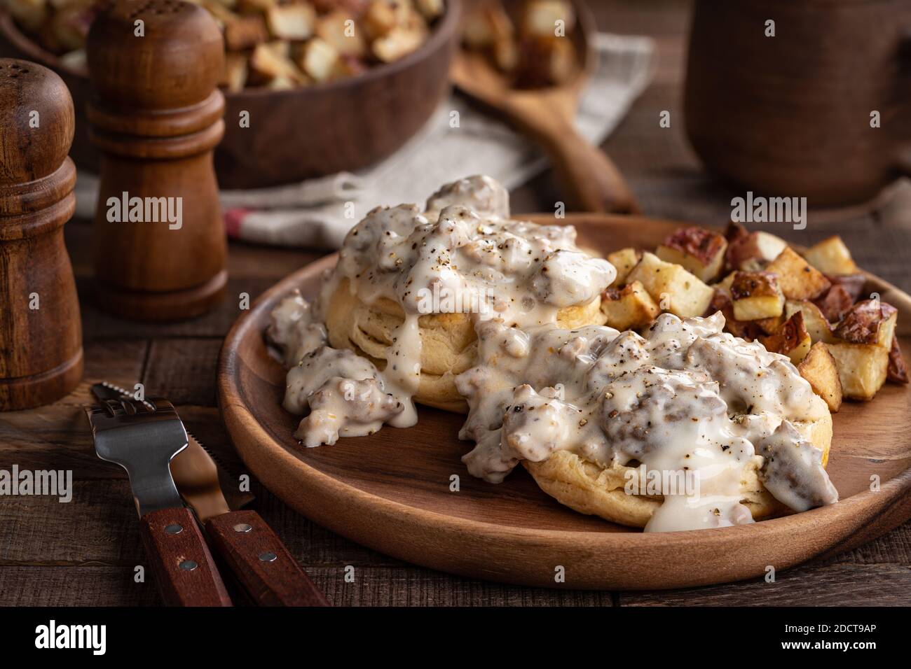 Crostini con sugo di salsiccia e patate fritte su A. piastra di legno Foto Stock