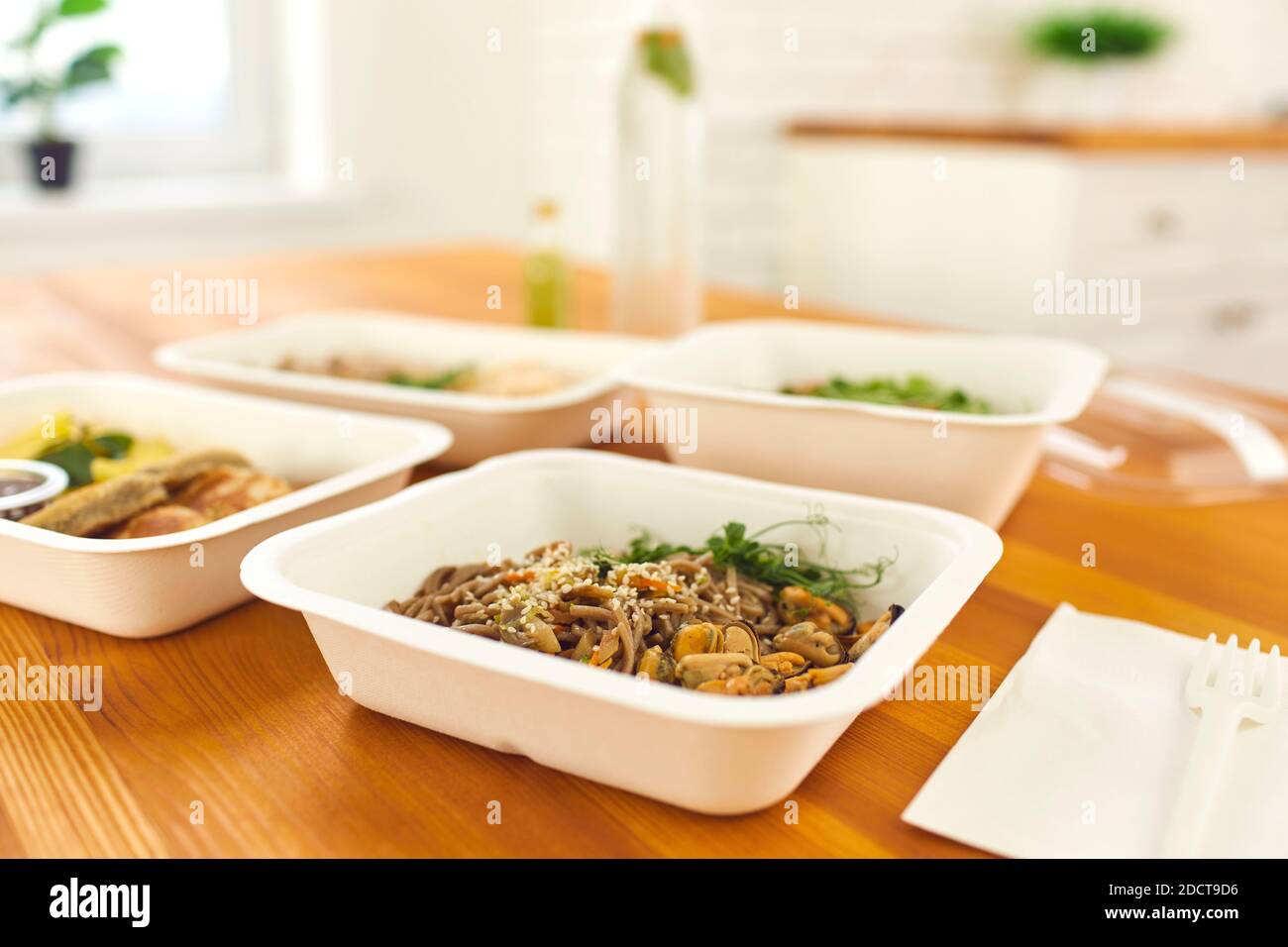 Primo piano di contenitori con una sana cena pronta con tagliatelle, cozze e micrograni sul tavolo. Foto Stock