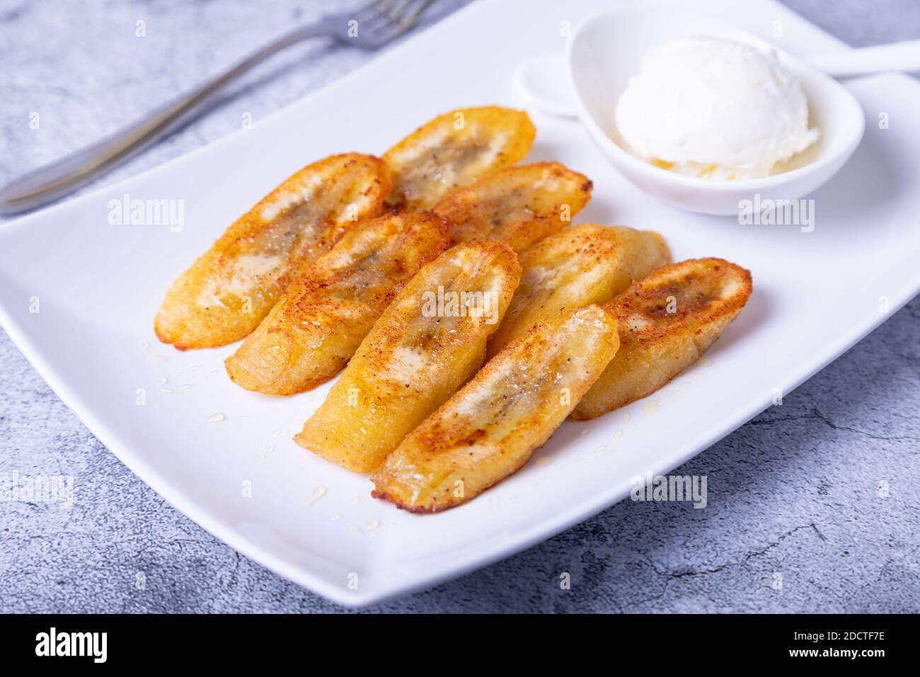Banane fritte con miele, cannella e gelato. Primo piano. Foto Stock
