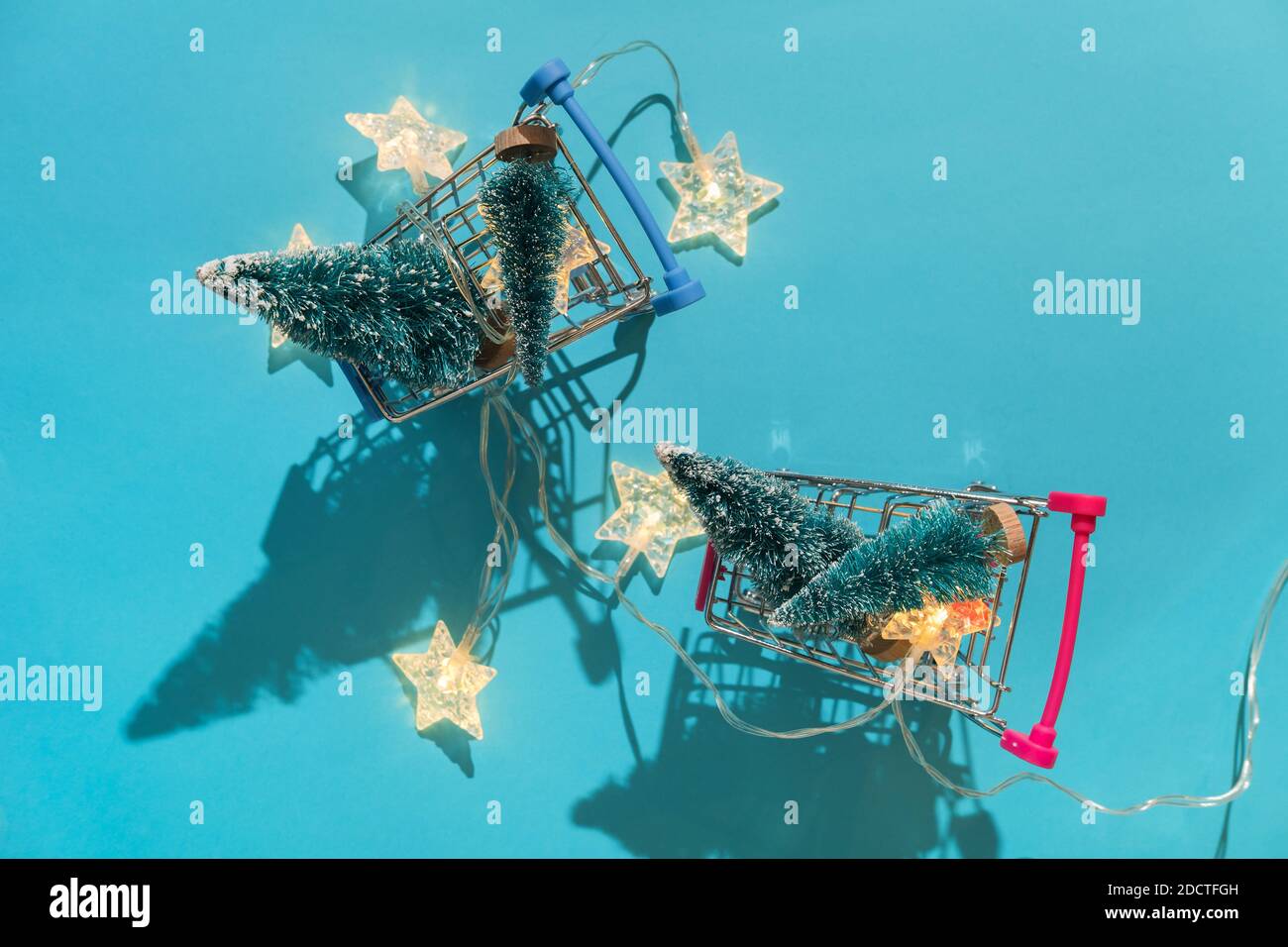 Natale sfondo festivo minimo con stelle garland in cesto supermercato, alberi giocattolo. Abstract Natale e Capodanno colore sfondo blu ai aqua Foto Stock