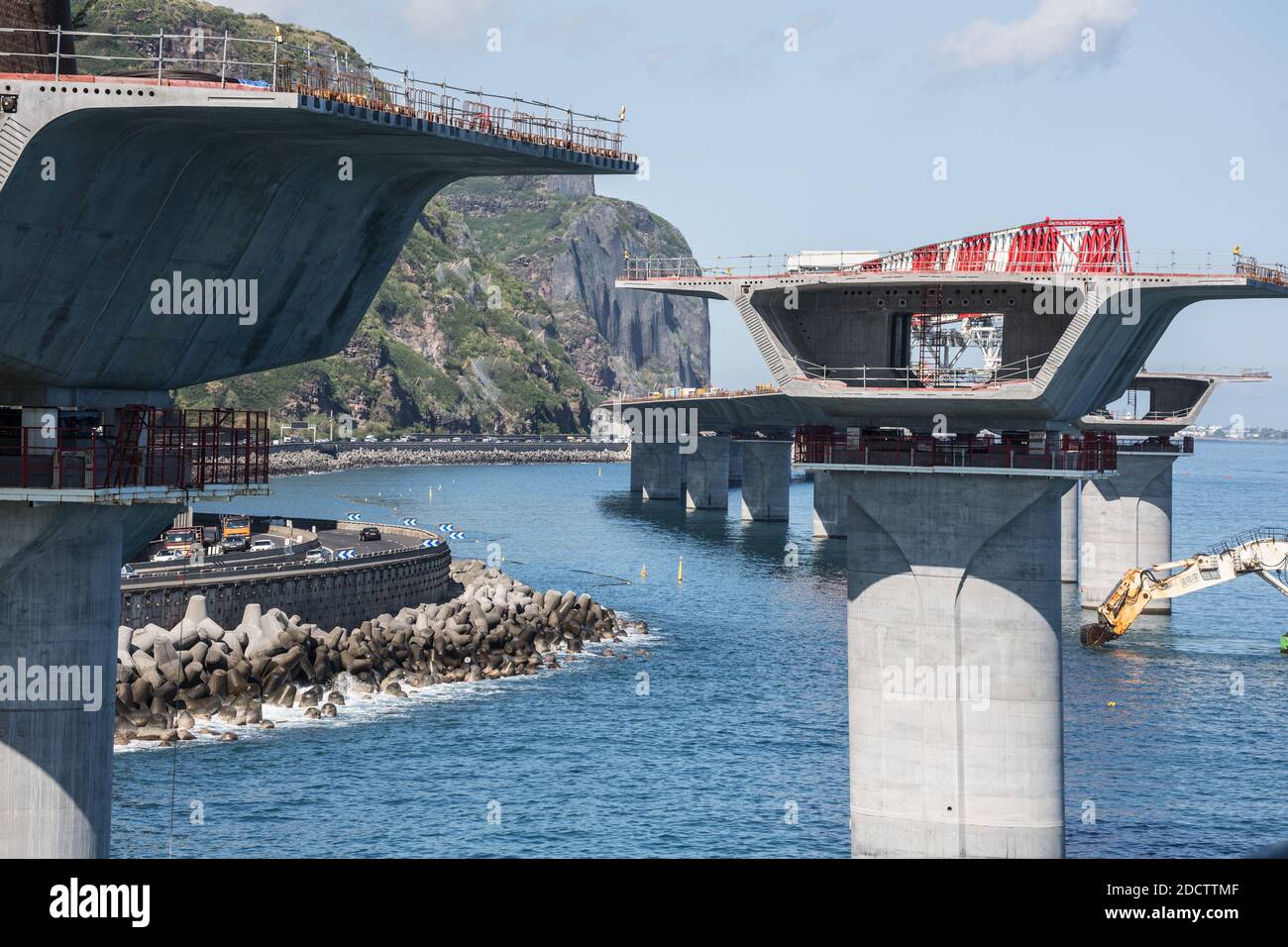 NESSUN WEB/NESSUNA APP - ESCLUSIVA. Vista generale del cantiere della Nuova autostrada costiera (Nouvelle Route du Littoral) con il lanciaponti (rosso e bianco) che depone i voussoirs (elementi a forma di cuneo) su entrambi i lati delle colonne del viadotto, nell’Isola di la Reunion, Francia nell’ottobre 2017. La nuova autostrada offshore di 12.3 km collegherà Saint-Denis, la capitale amministrativa dell’isola, con la possessione e sostituirà la strada rocciosa esistente soggetta a cadute di roccia e inondazioni durante tempeste tropicali. Avrà tre corsie in ogni direzione e migliorerà il trasporto una volta completato nel 2018. Esso Foto Stock