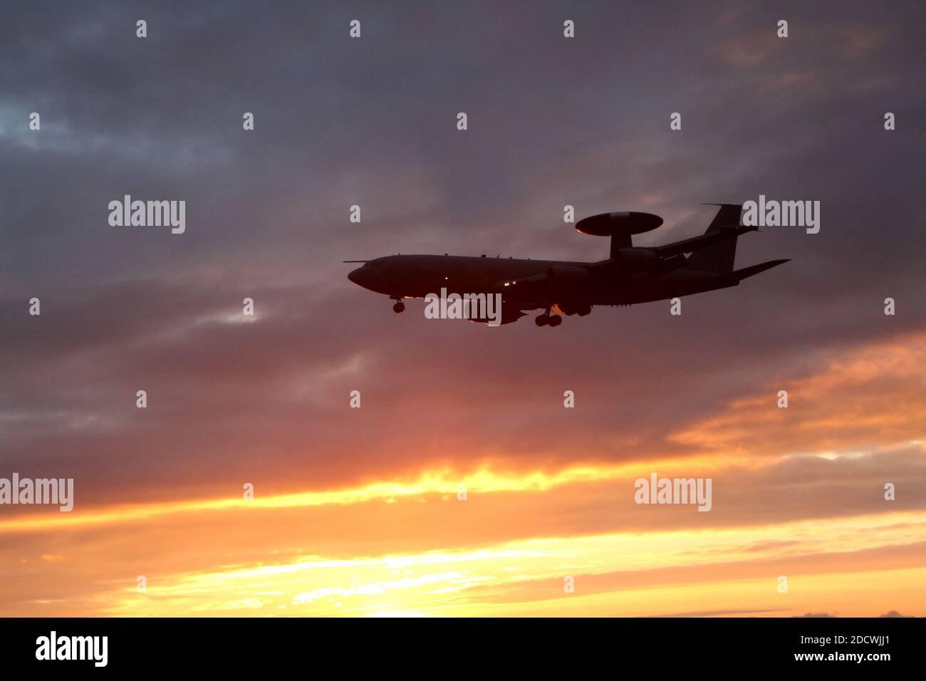 Aeroporto di Glasgow Prestwick , Ayrshire, Scozia, Regno Unito. L'AWACS (Airborne Warning and Control System) sul circuito di allenamento si avvicina alla pista ed è in una silhouette che si staglia contro il tramonto sulla costa occidentale della Scozia Foto Stock
