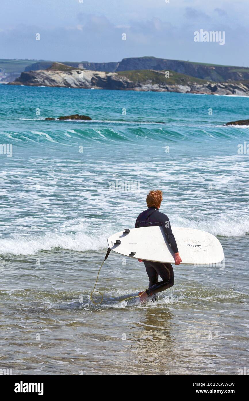 Surfer che entra nell'oceano a Great Western Beach a Newquay, Cornovaglia, Inghilterra Foto Stock
