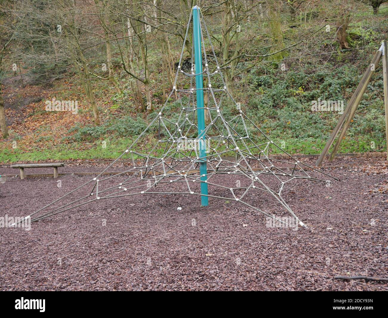 Corda per bambini che arrampica rete piramidale forma verde palo centrale in metallo corteccia di legno su alberi di pavimento in background Foto Stock