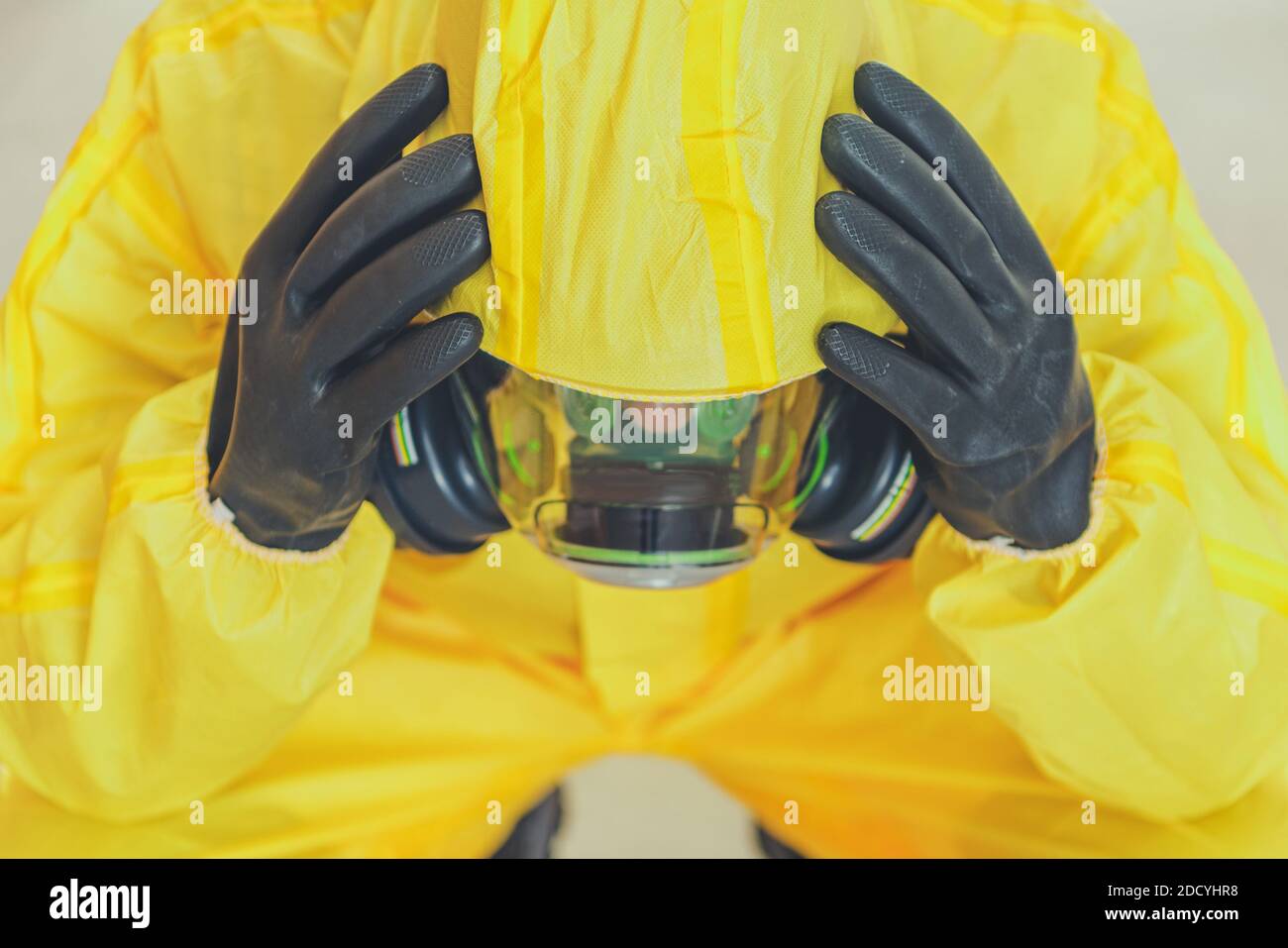 Uomini in tuta gialla Hazmat e maschera di protezione del respiro che allentano la sua mente. Concetto di lavoratore sanitario devastato. Covid-19 tema delle questioni mentali pandemiche. Foto Stock