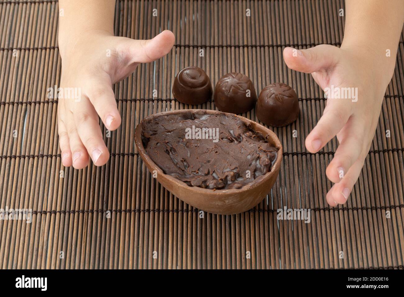 Solo le mani di un bambino che raccoglie l'uovo di Pasqua al cioccolato. Ripieno di cioccolato fondente e noci. Dolce tradizionale brasiliano. Foto Stock