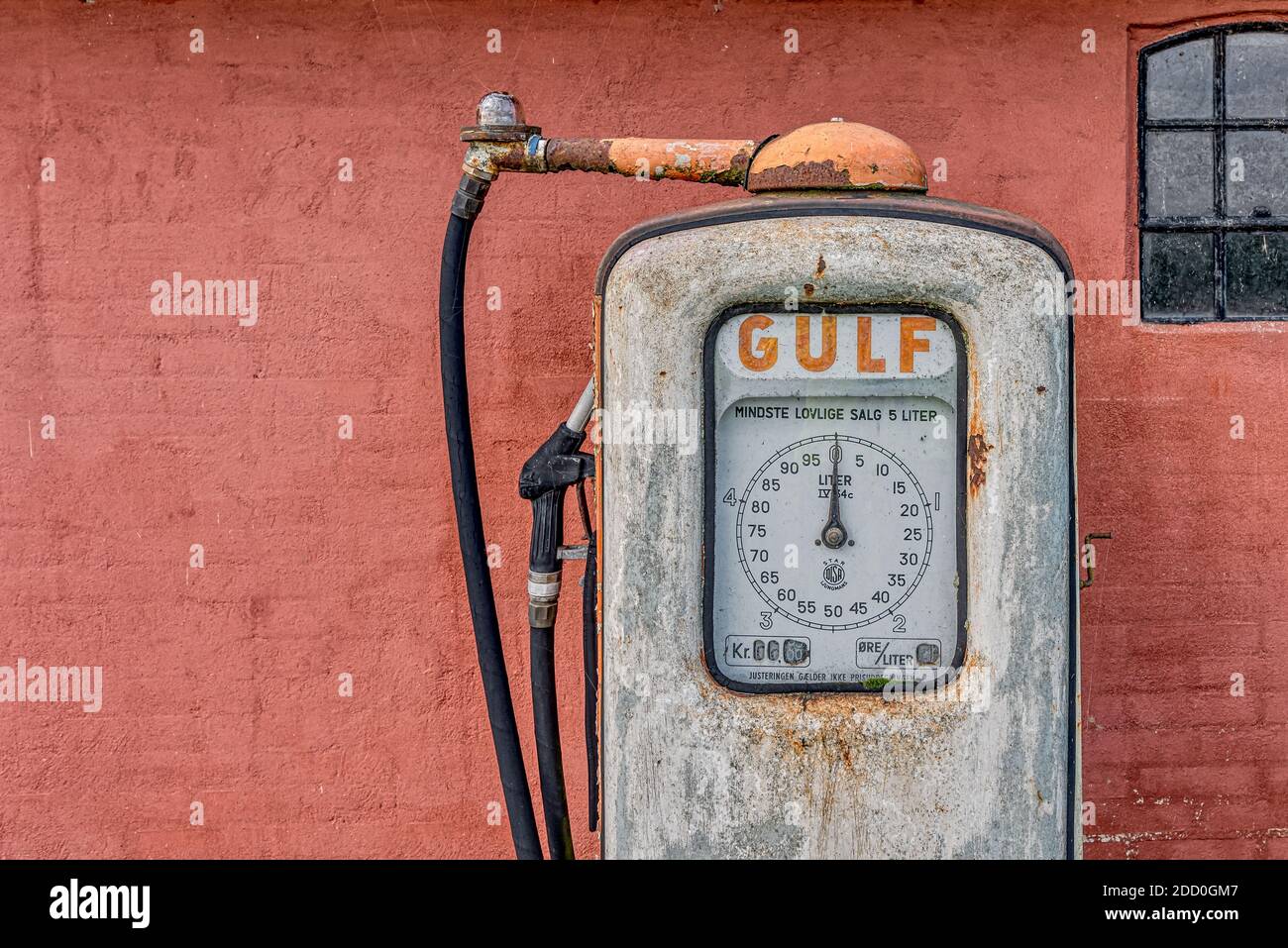 Una pompa a gas arrugginita abbandonata per la benzina del Golfo contro una parete di mattoni dipinti di rosso, Holl, Danimarca, 15 novembre 2020 Foto Stock