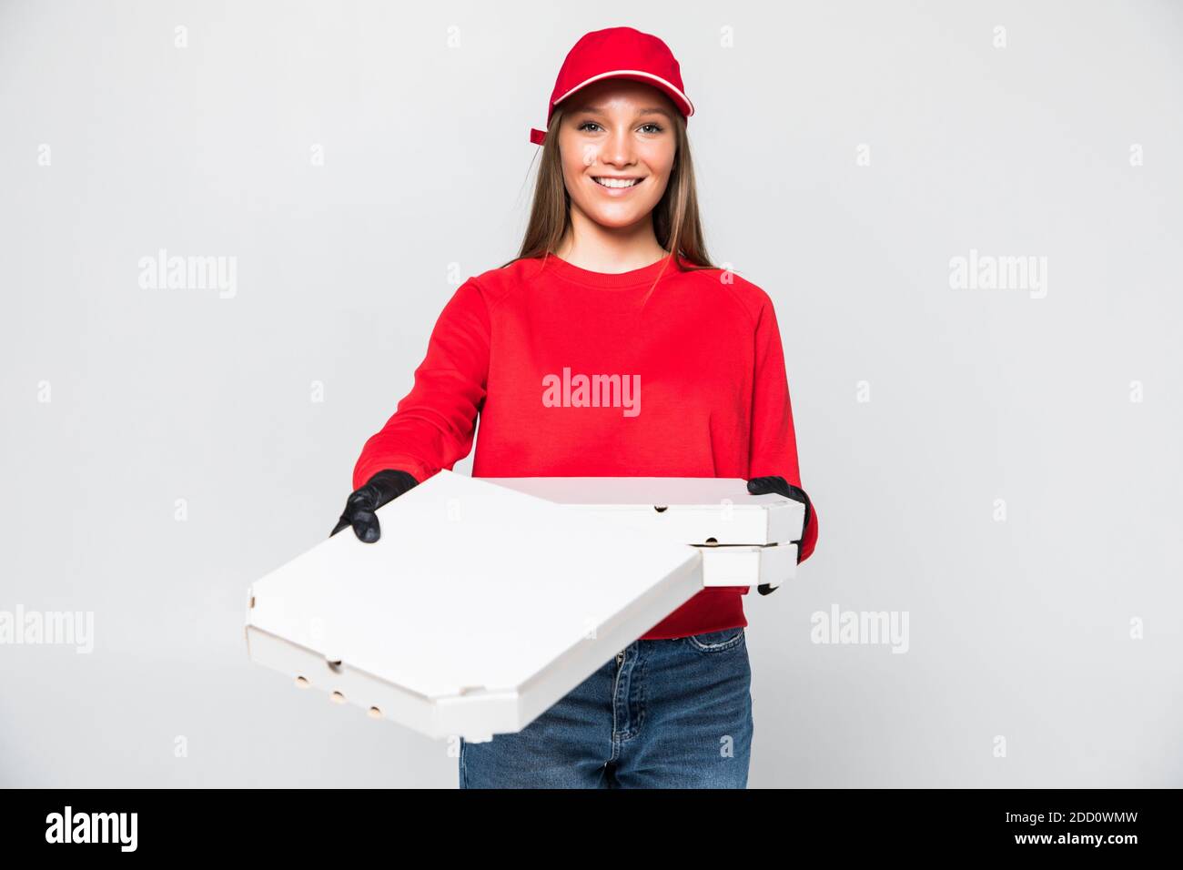 Consegna donna dipendente in rosso cappellino bianco t-shirt lavoro uniforme il corriere in attesa di servizio porta la pizza ordine del cibo in cartone scatola piatta isolata su bianco ba Foto Stock