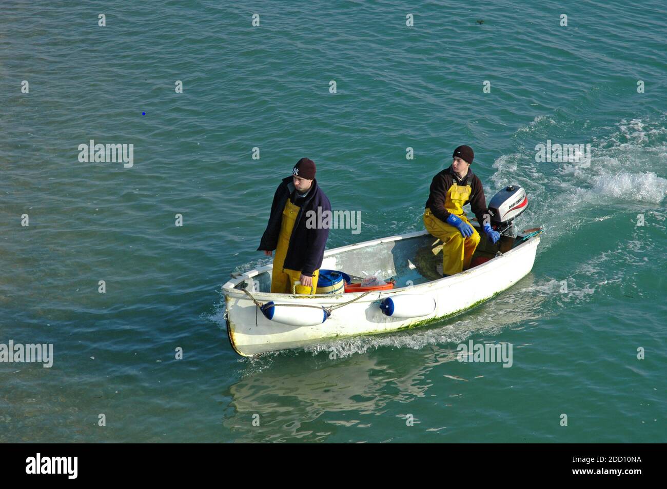Due pescatori di Selsey, inglesi, arrivano a riva in una piccola barca dopo la pesca del mattino. Selsey, Sussex occidentale. Inghilterra. Febbraio, rilascio del modello Foto Stock