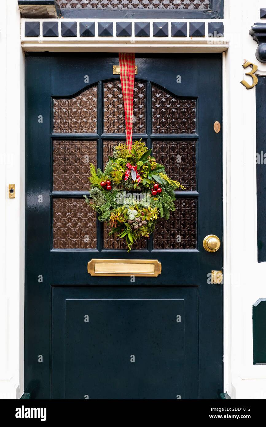 Corona di Natale sulla porta d'ingresso vintage all'esterno. Veranda porta anteriore decorata con decorazioni natalizie wreath. Esterno tradizionale di Natale Foto Stock