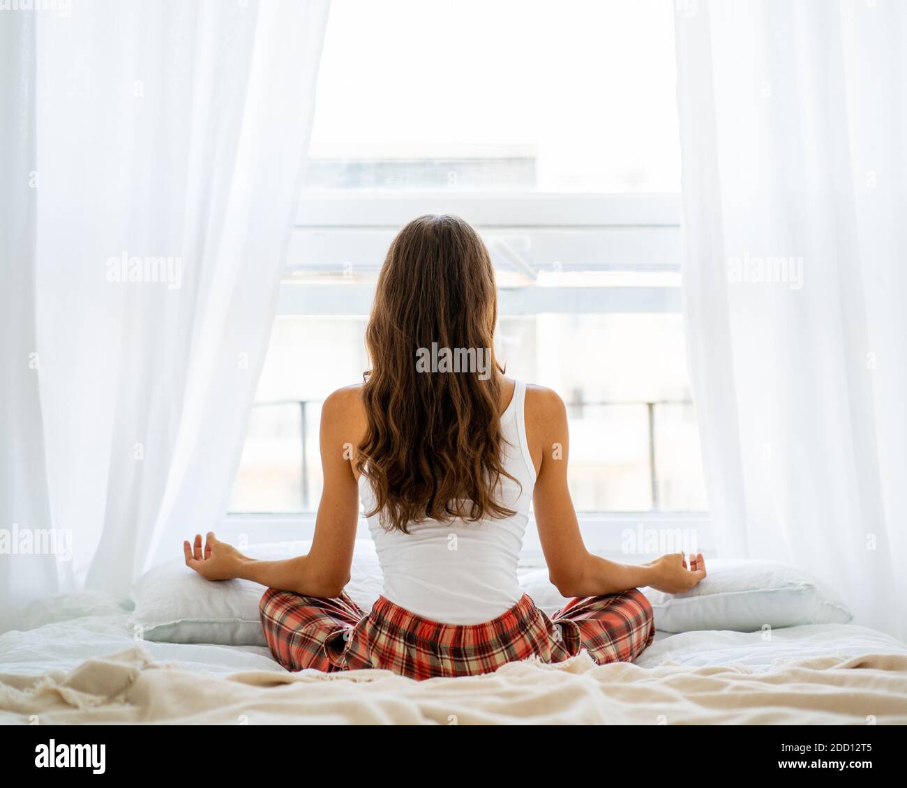 Vista posteriore della donna yoga posa in letto dopo il risveglio, entrando nuovo giorno Foto Stock