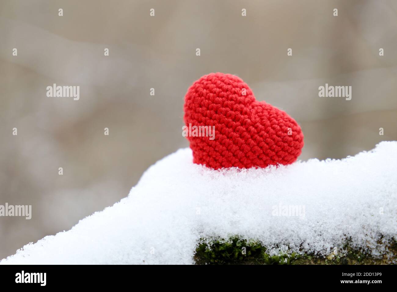Amore cuore, rosso lavorato a maglia simbolo della passione nella neve nel parco invernale. Sfondo per la carta di San Valentino Foto Stock