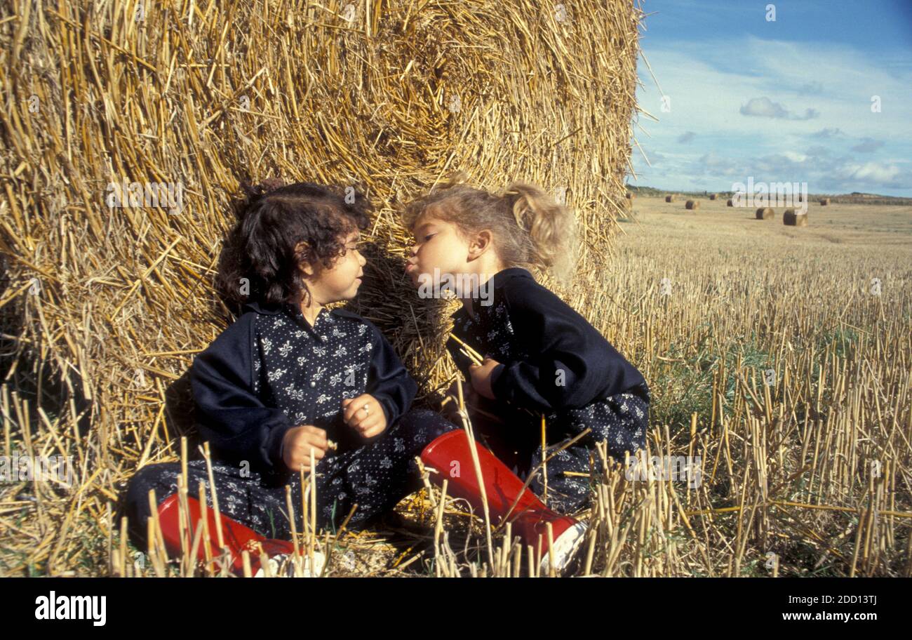 due piccole sorelle che giocano tra gli haystack Foto Stock