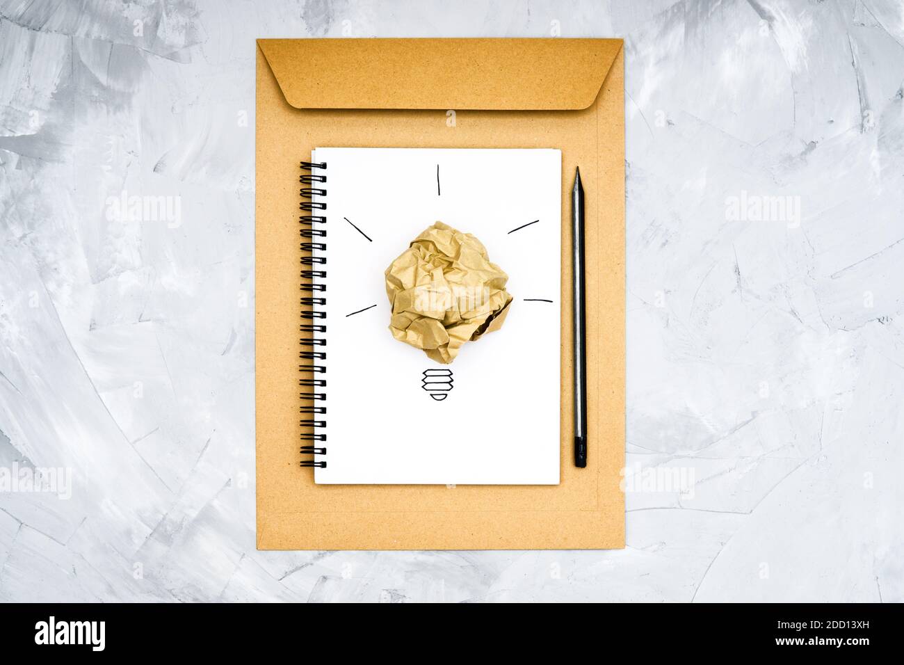 Simbolo della lampadina costituito da una sfera di carta sminuzzata e da uno schizzo su un notebook a spirale. Concetto di processo creativo. Foto Stock