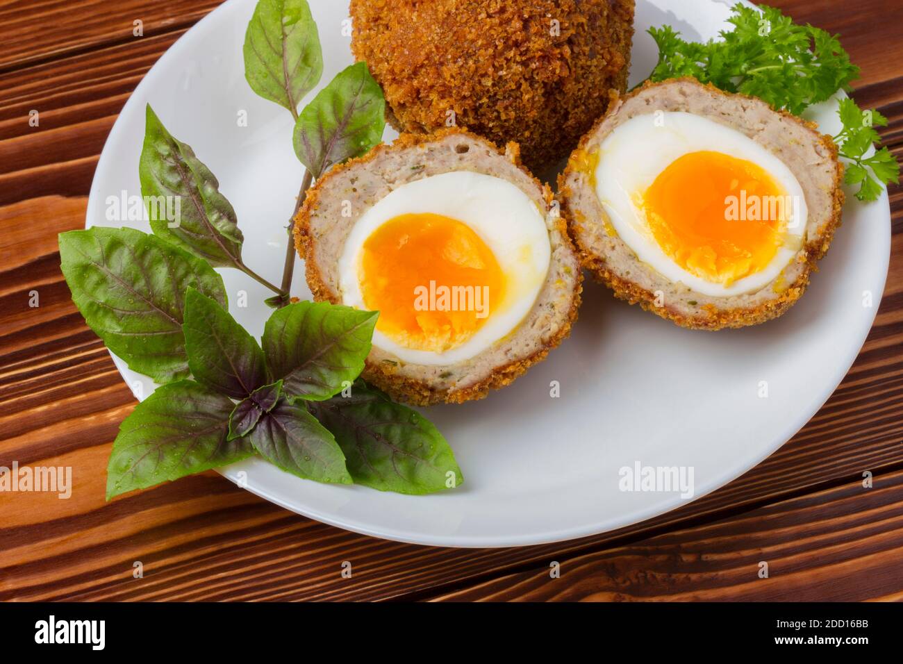 Uova scozzesi cotte su piatto di porcellana bianca da vicino Foto Stock