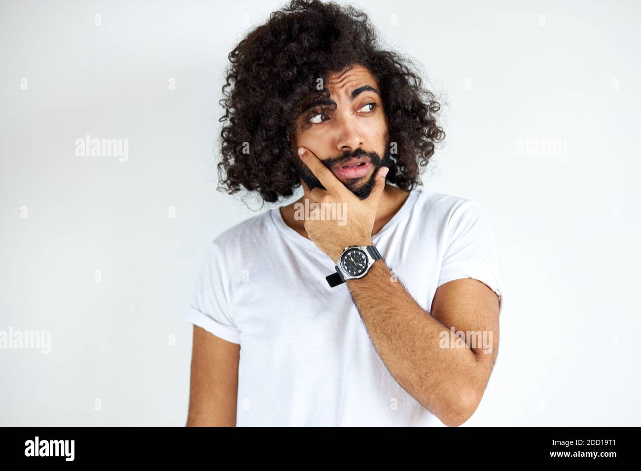 il maschio arabico determinato con la barba sta pensando e guardando preoccupato, in piedi contro sfondo bianco. Foto Stock