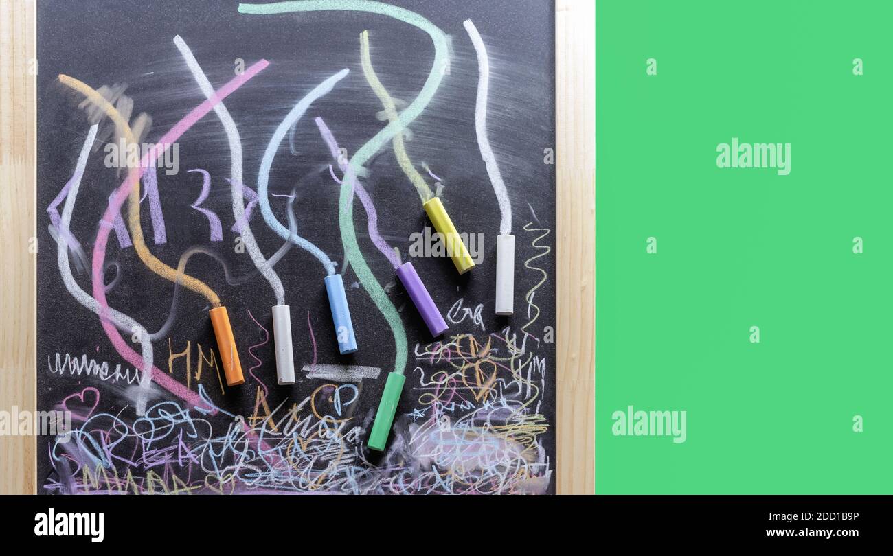 Lavagna in gesso con pastelli colorati per la scrittura e il disegno. Foto Stock
