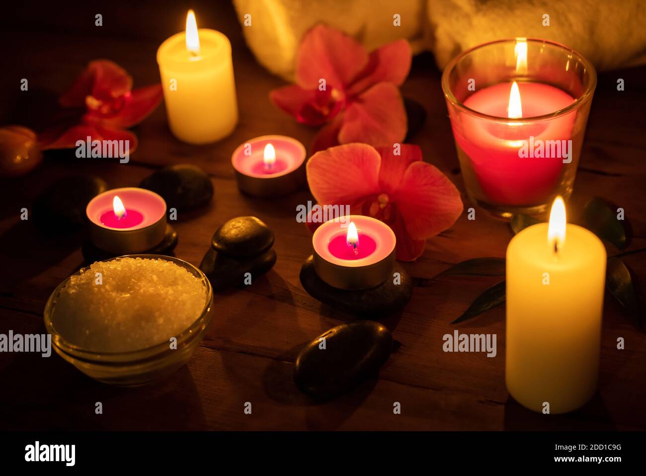 concetto di trattamento di bellezza spa - candele con fiori e massaggio pietre su sfondo di legno Foto Stock