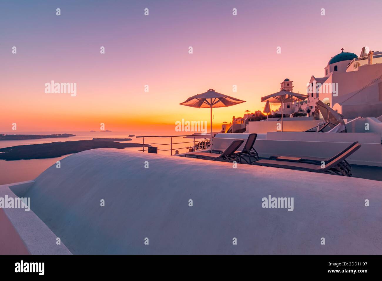 Terrazza al tramonto sull'isola di Santorini, Grecia. Splendido resort con vista sulla caldera e tramonto. Relax vibrazioni, ombrellone e sedie, tavolo. Vacanze estive Foto Stock