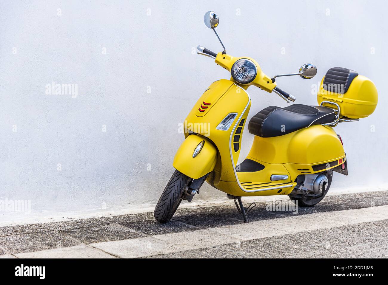 Vecchio scooter Vespa sulla strada in tradizionale strada in pietra, strada di fronte di muro bianco. Foto Stock