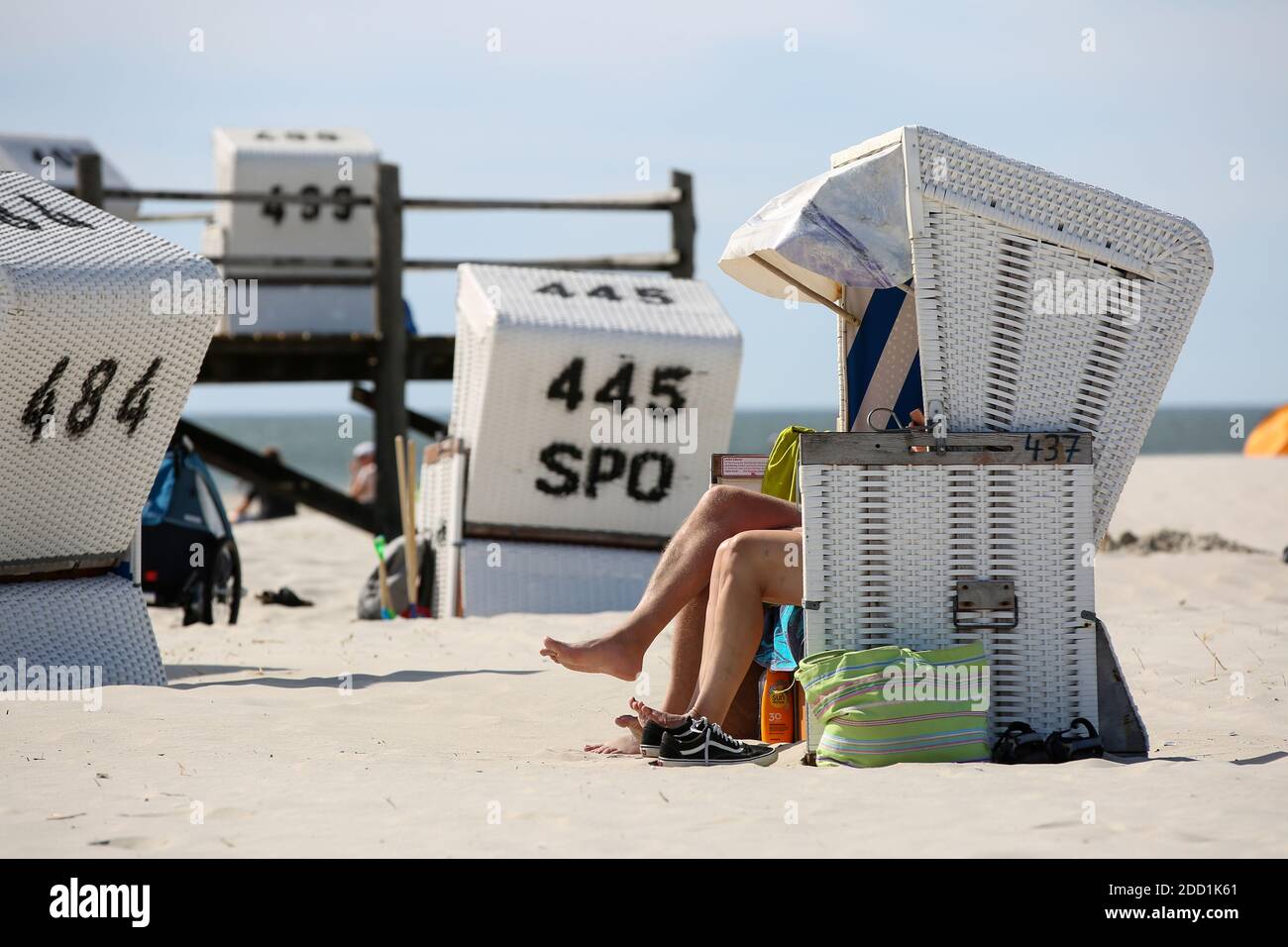 Urluber sitzen bei Sonnenschein am Strand von Sankt Peter Ording in einem Strandkorb. Foto Stock