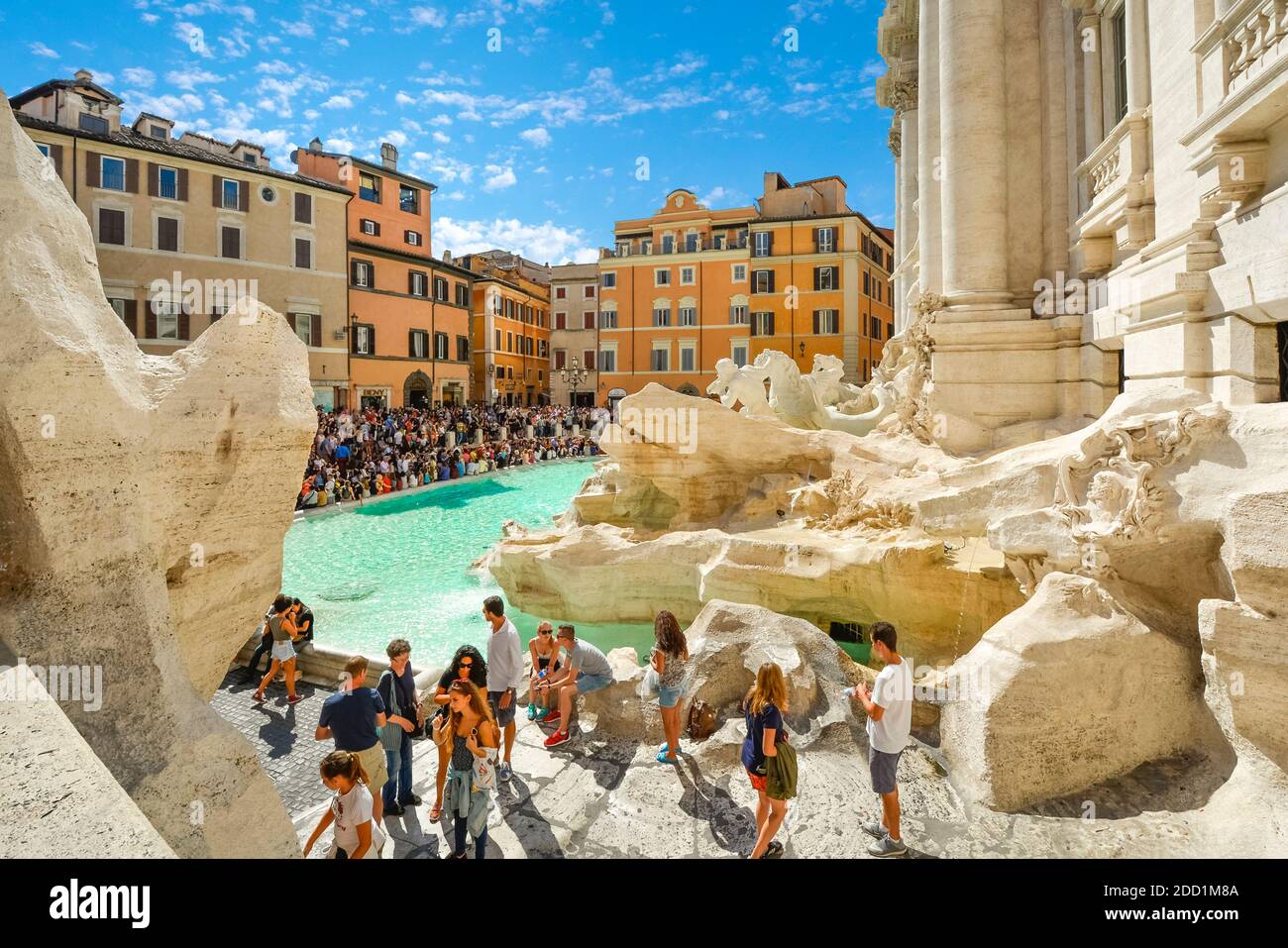 Una vista laterale della Fontana di Trevi in Piazza di Trevi mentre i turisti si godono una giornata di sole nel centro di Roma. Foto Stock