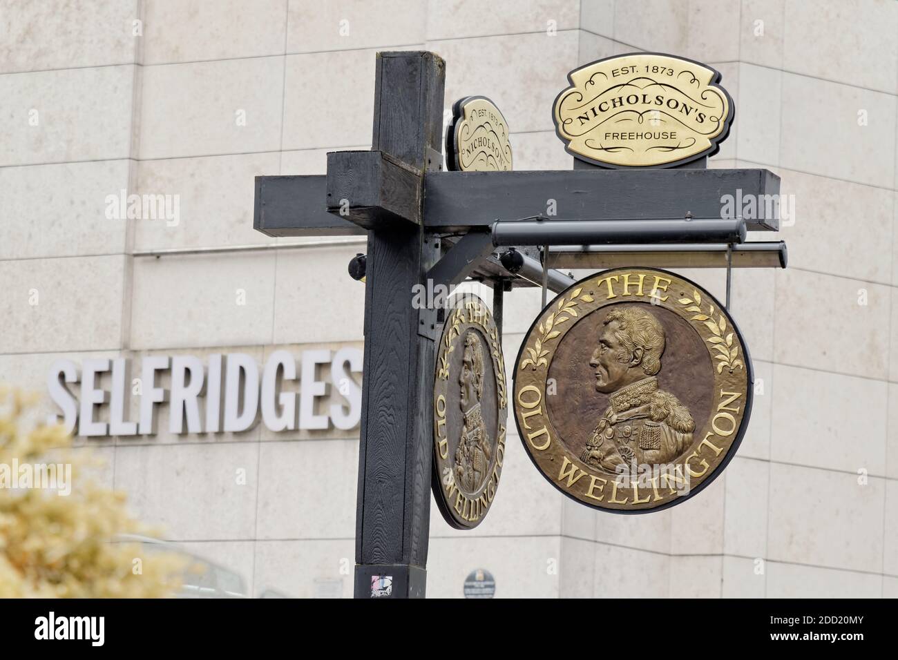 Insegna del pub Old Wellington vicino alla Cattedrale di Manchester con il grande magazzino Selfridges sullo sfondo. Foto Stock