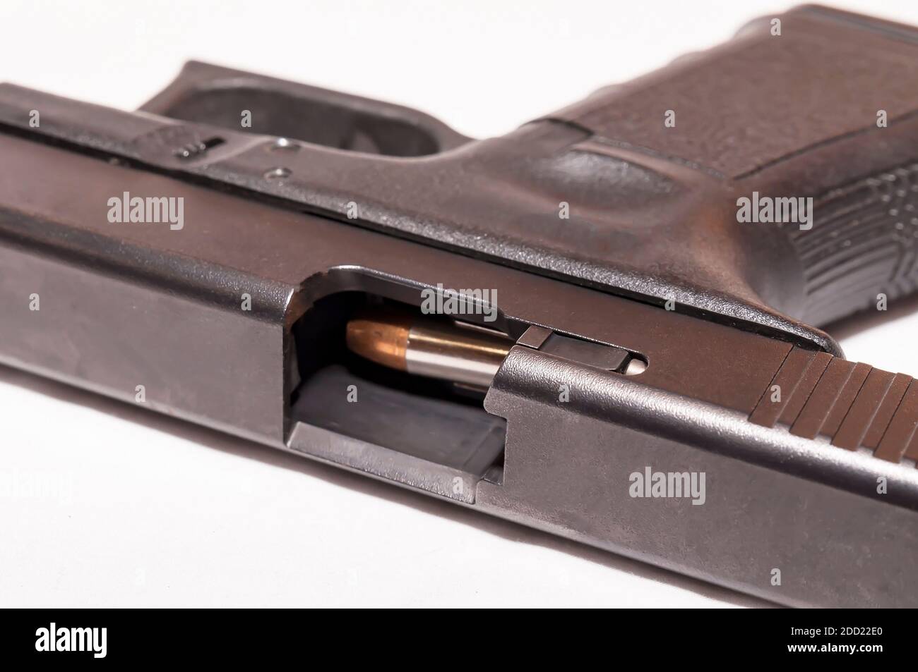 Una pistola nera da 9 mm con una diapositiva aperta che mostra una pallottola che sta per essere smussata su uno sfondo bianco Foto Stock