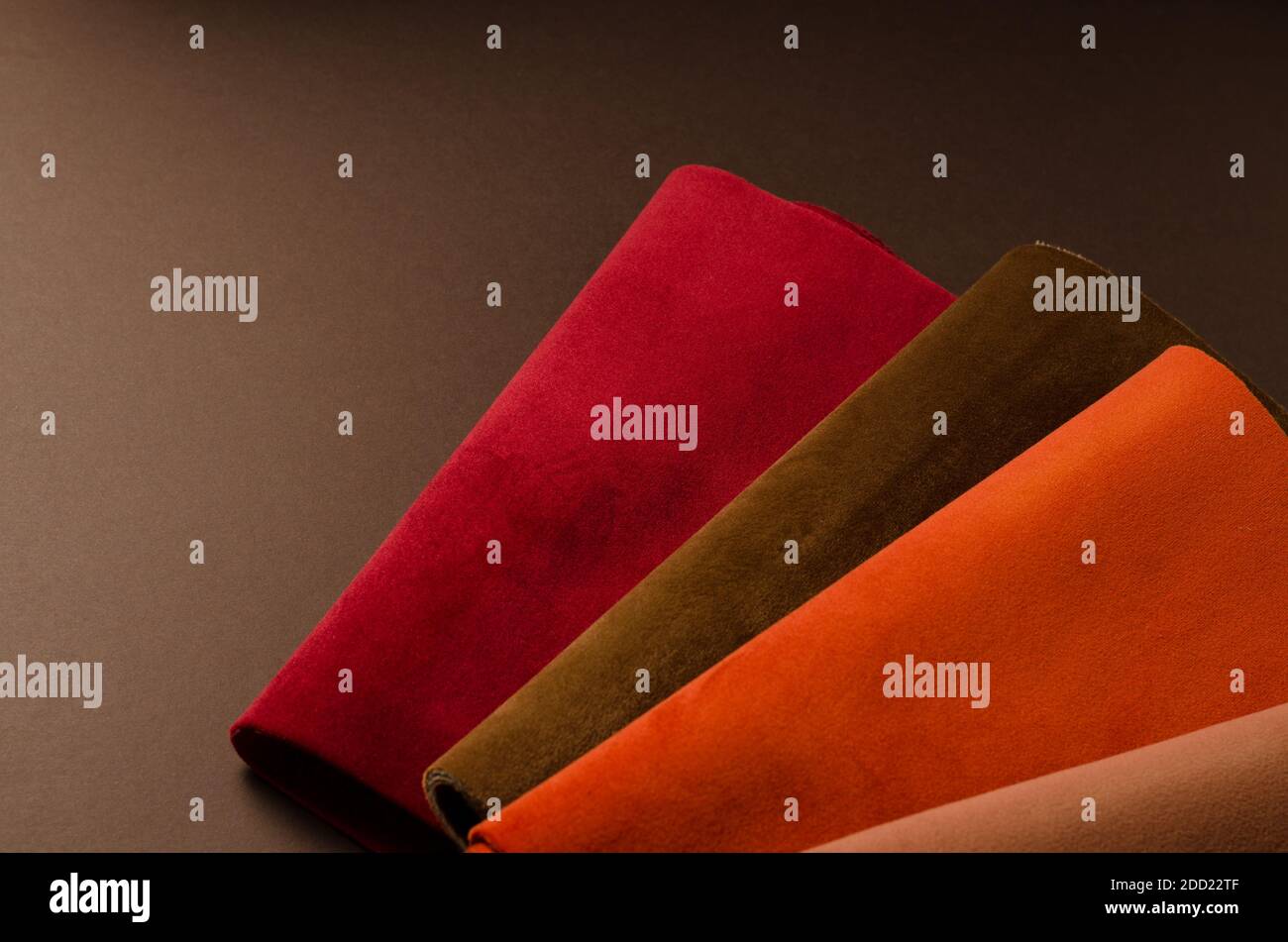 Una collezione luminosa di campioni di tessuto vellutato rosso, marrone e arancione colorato. Tessuto trama sfondo Foto Stock