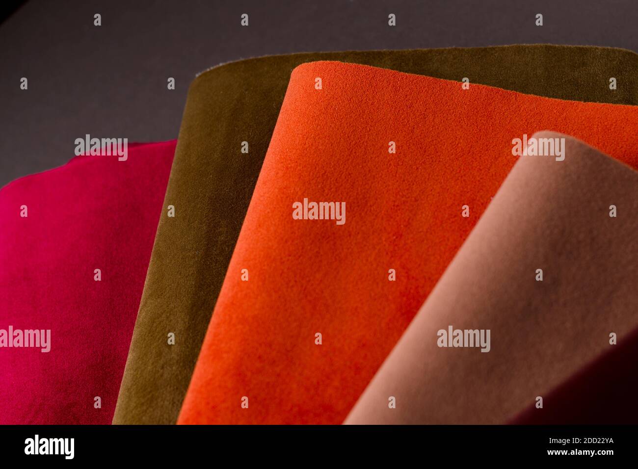 Una collezione luminosa di campioni di tessuto vellutato rosso, marrone e arancione colorato. Tessuto trama sfondo Foto Stock