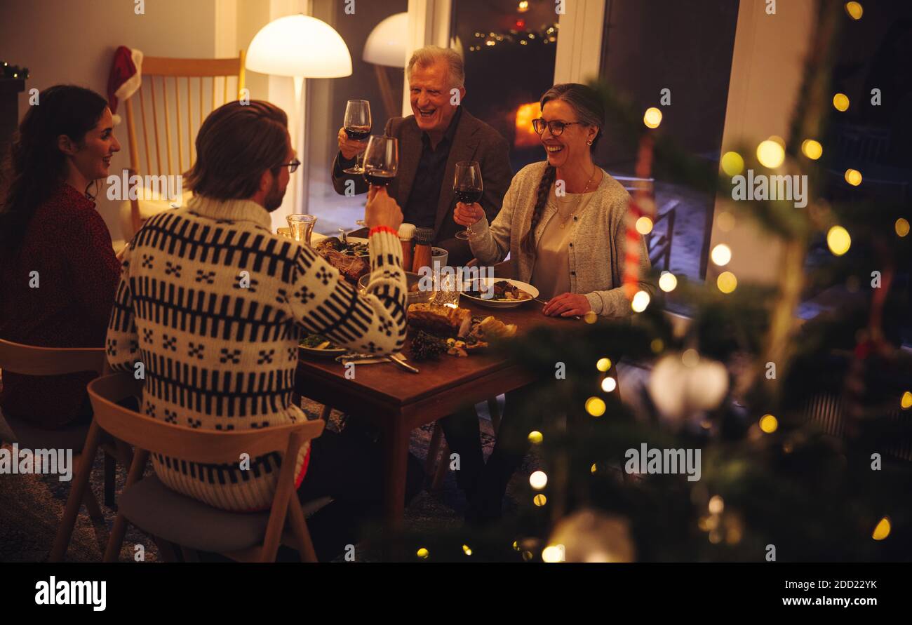 La famiglia europea brinda il vino e gusterai la cena la vigilia di Natale. Famiglia di due generazioni che ha una cena di Natale insieme. Foto Stock