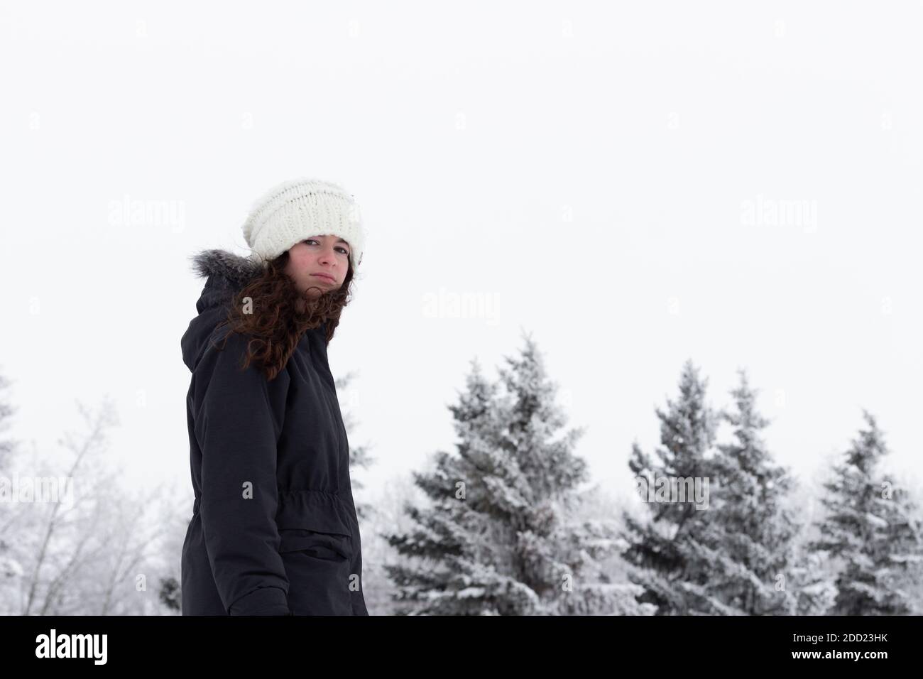 Giovane adulto, ragazza teen, camminando fuori in inverno paesaggio tempo, neve e gelo su alberi in background guardando la fotocamera MR immagini di persone con Foto Stock