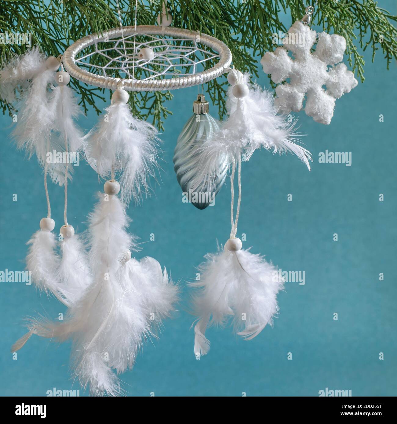 Dreamcachter bianco con piume e natale bauble appeso sul ramo di thuja. Amuleto nativo americano, simbolo e patrimonio. Foto Stock