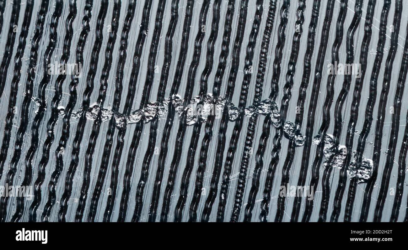 Foto macro ravvicinata della superficie di un disco di musica vinilico d'epoca che include groove, polvere e un tipico graffio superficiale. Foto Stock