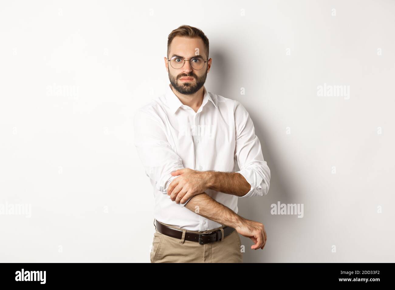 Uomo arrabbiato rotolare le maniche e guardare offeso, pronti a combattere, in piedi su sfondo bianco Foto Stock