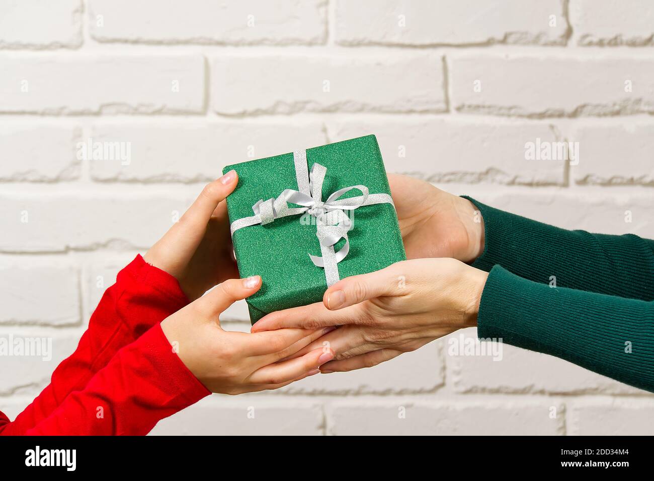 Mani femminili che tengono una piccola scatola regalo avvolta in carta da imballaggio. Dare e ricevere doni da persone care per natale, valentine, compleanno. Foto Stock